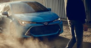 A blue 2019 Toyota Corolla Hatchback breaking on a dirt road.