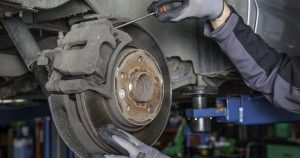 A mechanic working on replacing a pair of brake pads.