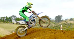 A dirt bike jumping over a dirt mound during a Motocross race.