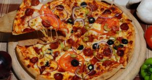 A delicious pizza with a slice cut out.