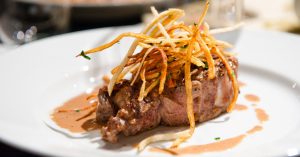 An amazing looking steak with fried onion strings.
